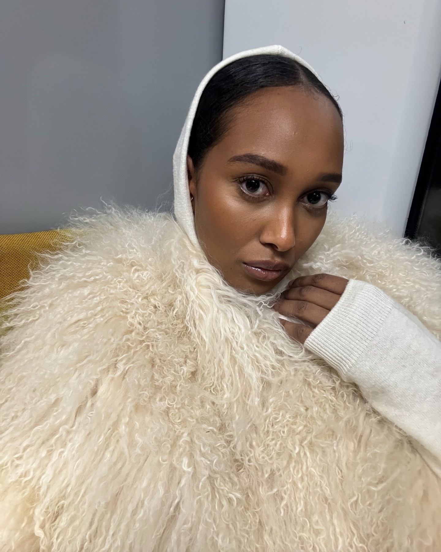Mona taking a selfie wearing a fur shawl.