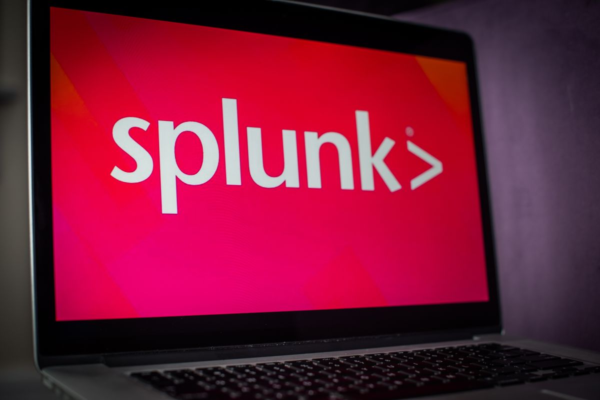 Splunk logo on a laptop with a bright pink background in a dark room