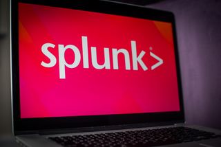 Splunk logo on a laptop with a bright pink background in a dark room