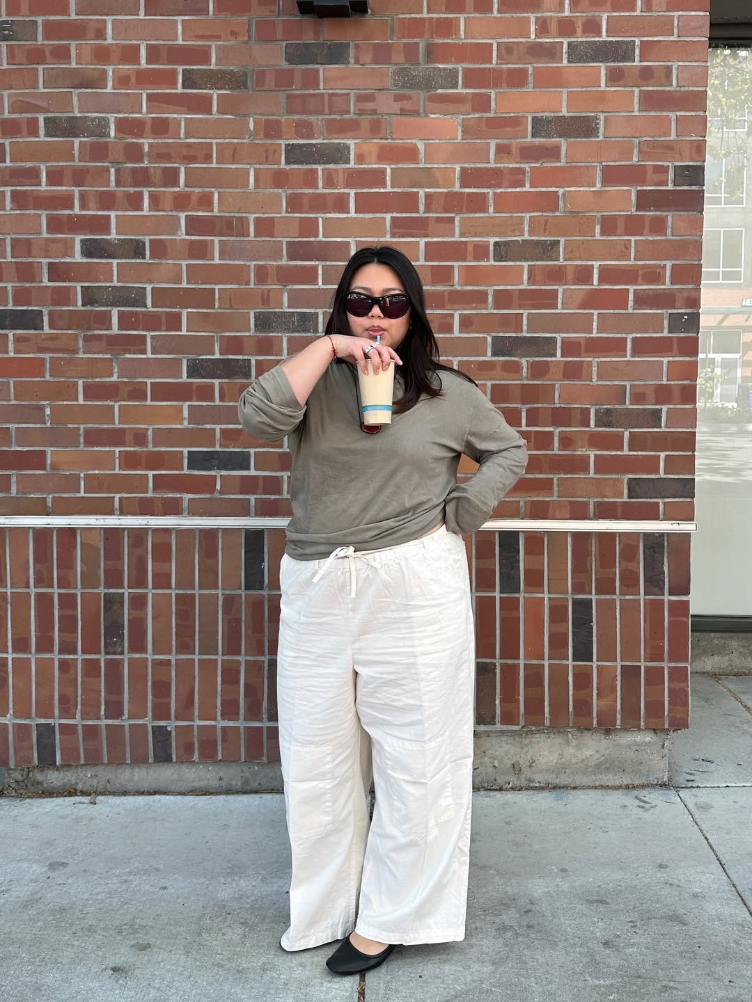 Woman wears green top, white linen trousers black shoes