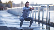 A woman in exercise clothing performing a squat as part of a leg workout