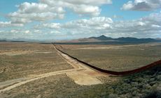 View of a border fence diving an otherwise open flat section of barren terrain.