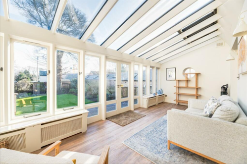 A conservatory with wooden panelled floors and a slanted roof