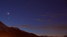A view of a deep purple night sky with a red glowing mountain range underneath a series of twinkling stars.