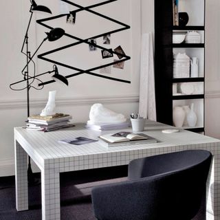 modern monochrome home room with checked design table grey chair black open shelving table lamp and pin board