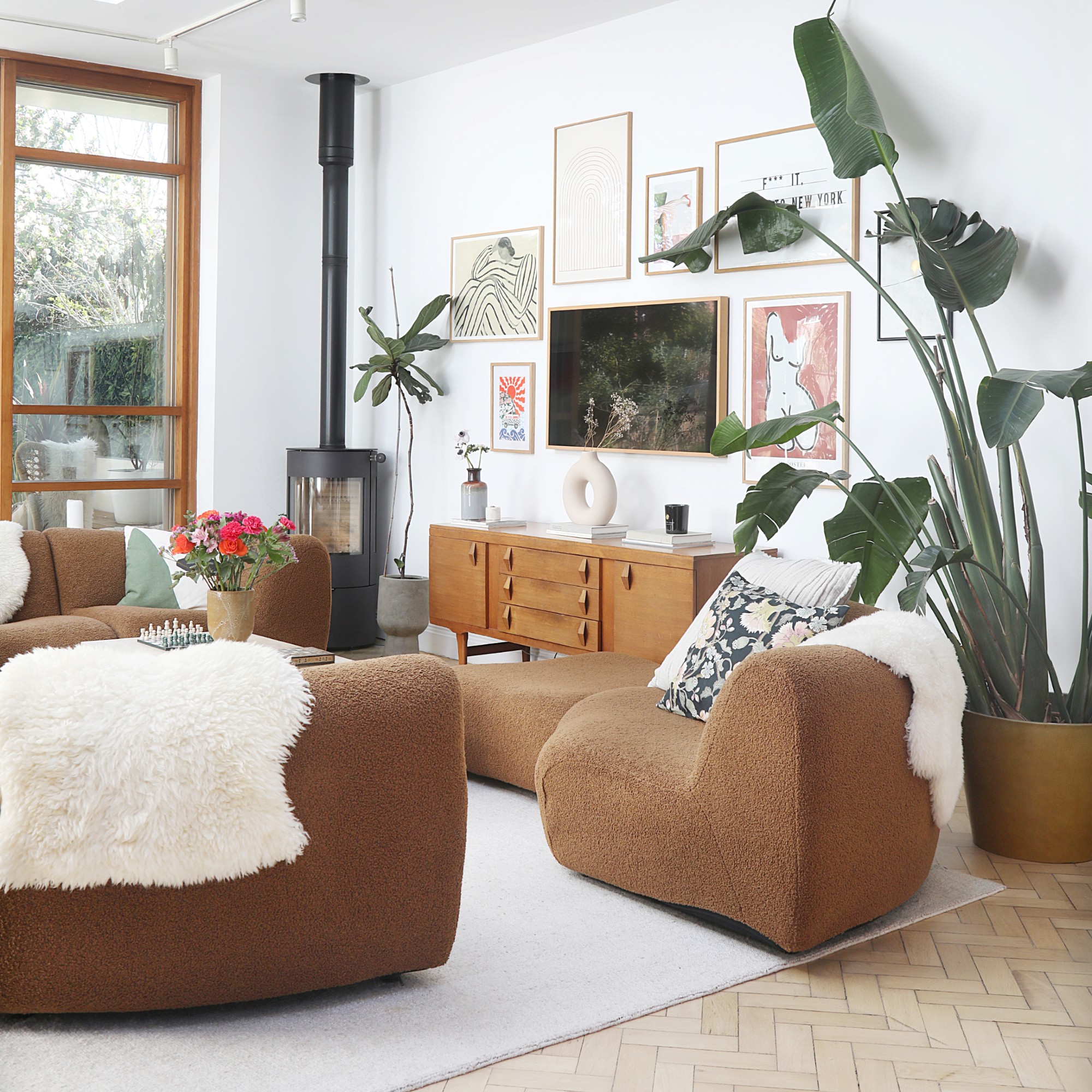 A white living room with a brown King Living 1977 modular sofa and a gallery wall