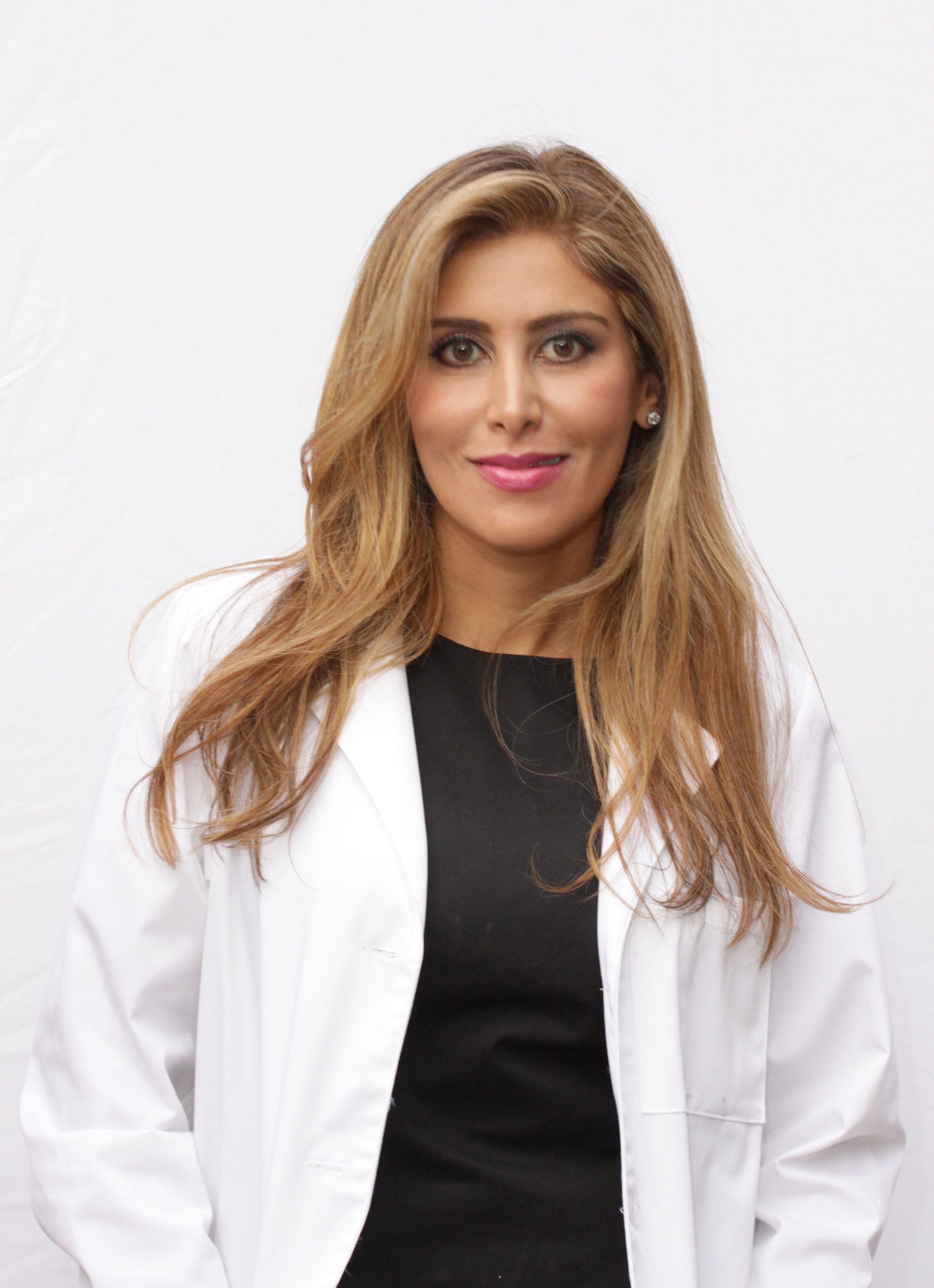 a woman with golden blonde hair in a white lab coat and black dress