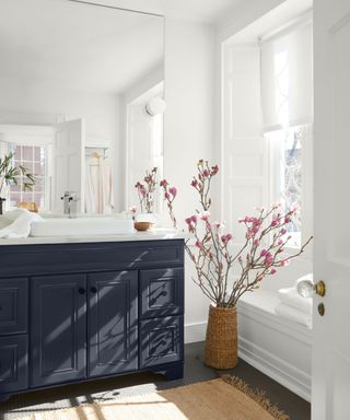 A bathroom with white walls and a large blue vanity unit and mirror