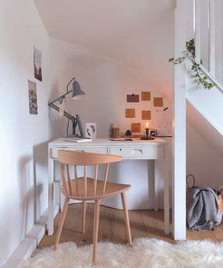 Under the stairs small home office idea by Period Living Magazine, with a small white desk and wooden chair under the stairs and a white fluffy rug on the floor