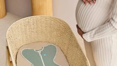 A pregnant mum standing next to a wicker bassinet from Love to Dream.