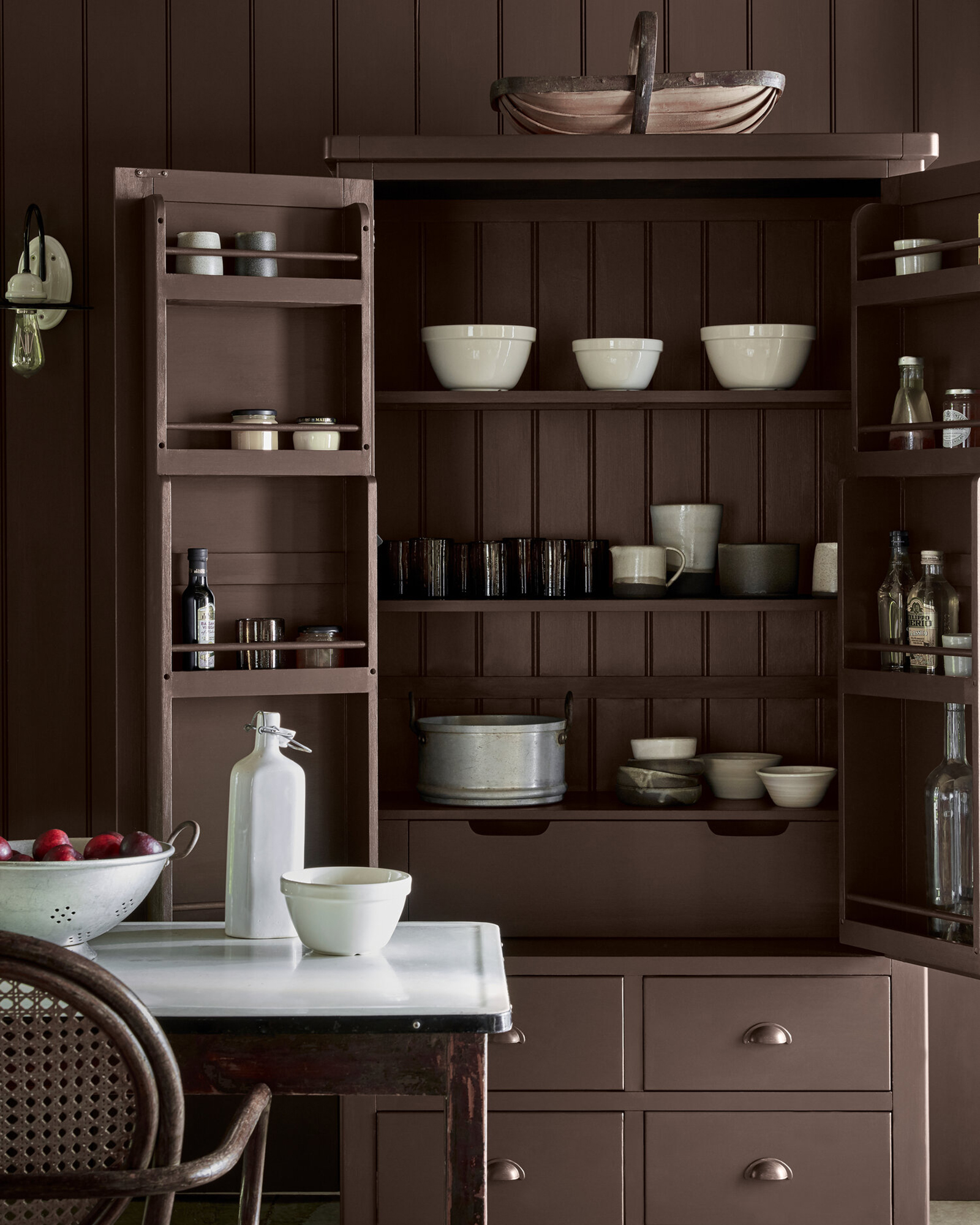 A dresser, table, chair and wall all painted deep brown, one of 2021's color trends