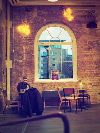 Image of a man in a coffee shop, taken on the OM System OM-3 with the OM System 25mm f/1.8 II lens