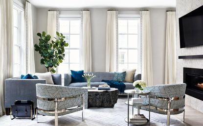 living room with light stone colored walls, tall windows, two light blue grey sofas