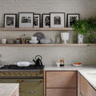 Modern kitchen range and fitted units with shelves and exposed painted brick wall and roof beams