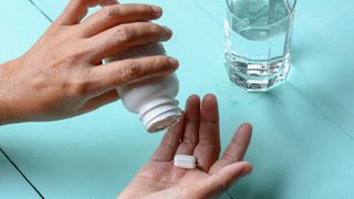 woman pouring supplement capsules onto her hand