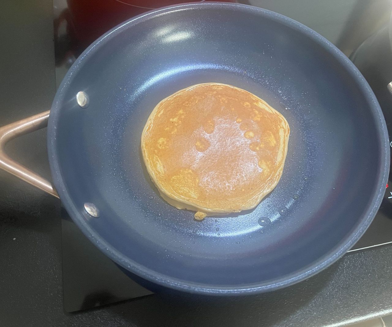 A golden pancake in a small blue ceramic frying pan