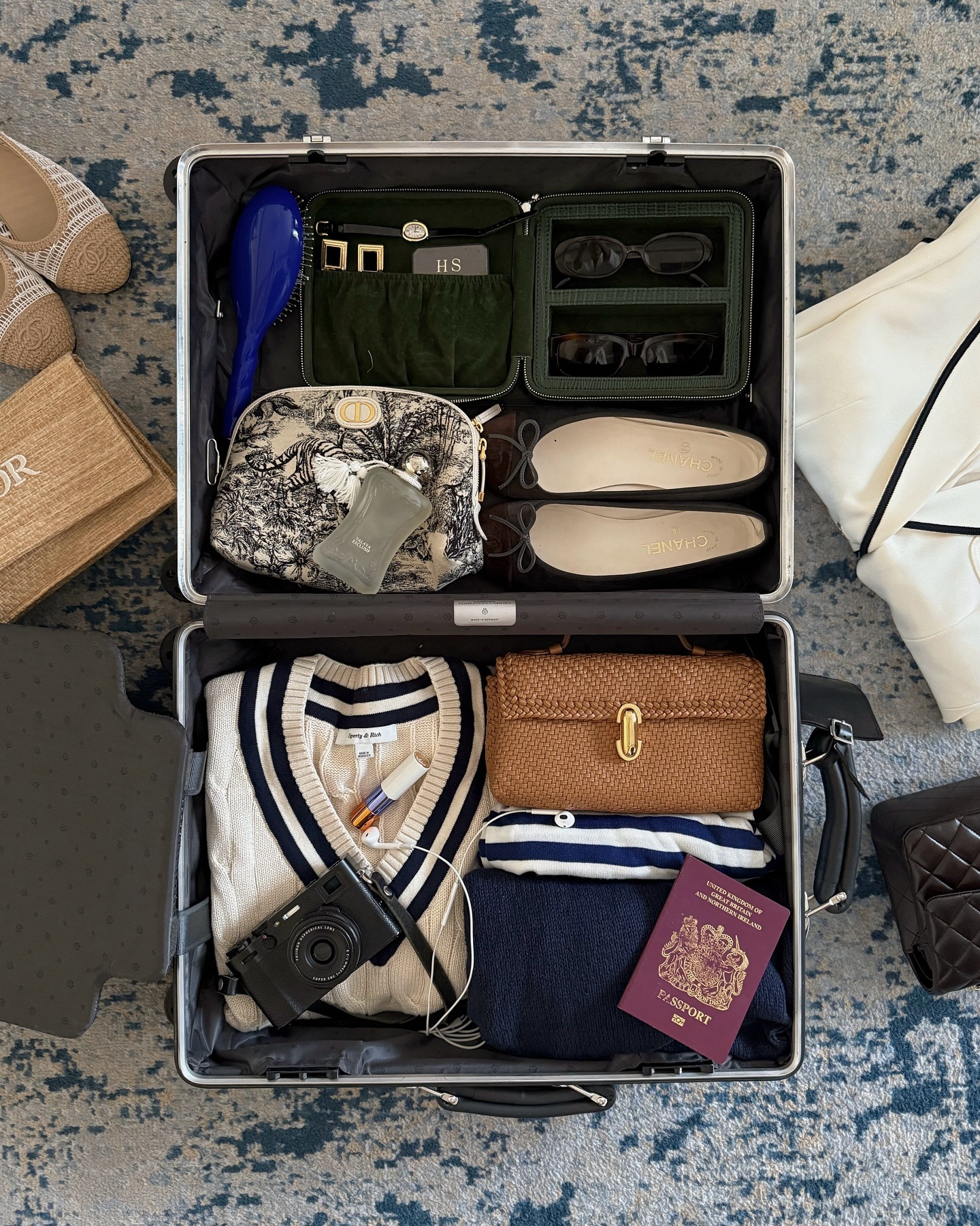 Fashion person Hannah Desai shows comfy travel outfit. In the image she shows a packed case, filed with clothes shoes bags and accessories.