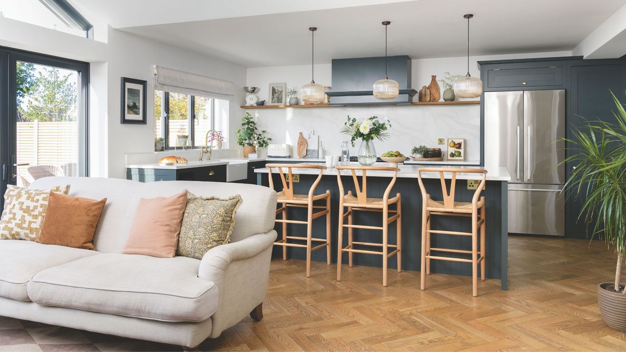 open plan kitchen extension with bar seating and grey sofa on wooden parquet floor 