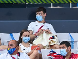 Tom Daley of Great Britain knits during the preliminary round of the men's 3m springboard at the Tokyo Aquatics Centre