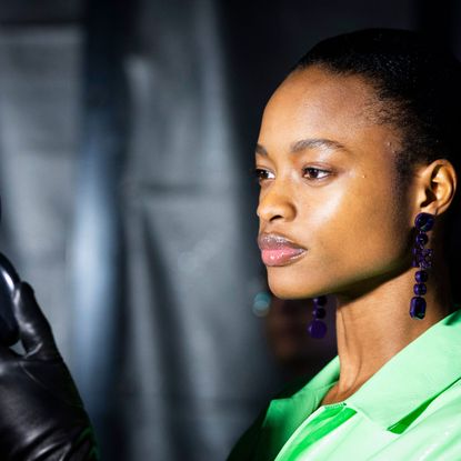 model with glowing skin wearing a green shirt and hanging earrings