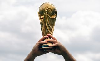 A man holds the FIFA World Cup in his hands.