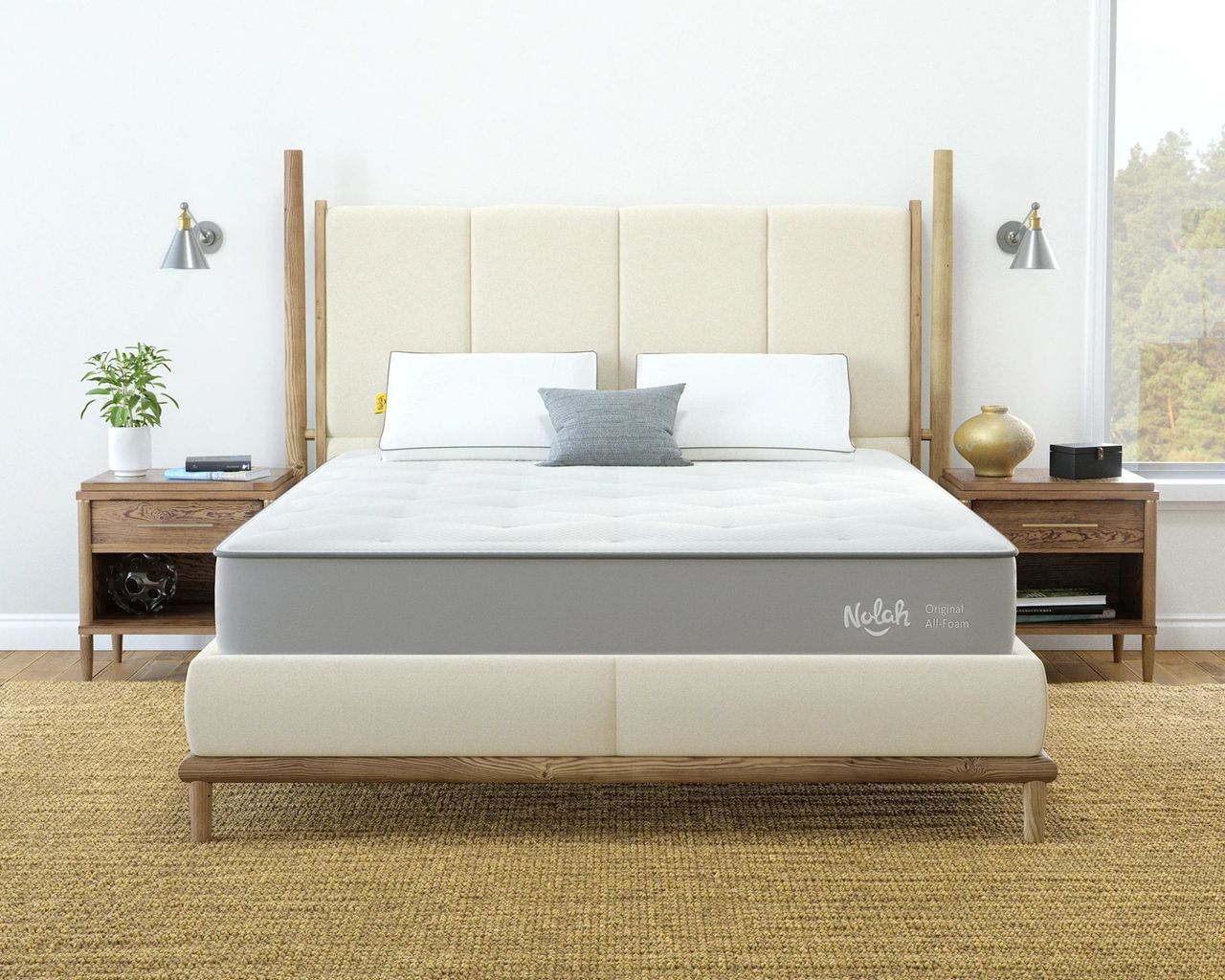 Nolah original mattress shown on a white bed in a white bedroom with jute rug, white walls, wooden nightstands, and large window