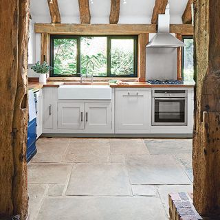 kitchen with white cabinet wooden beams on ceiling window and stove