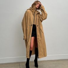 Rosie wears a long camel coat, black skirt, and black sock boots.