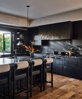 A dark, moody kitchen with marble backsplash and countertops