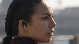 Woman wearing the JBL Under Armour Flash X earbuds.