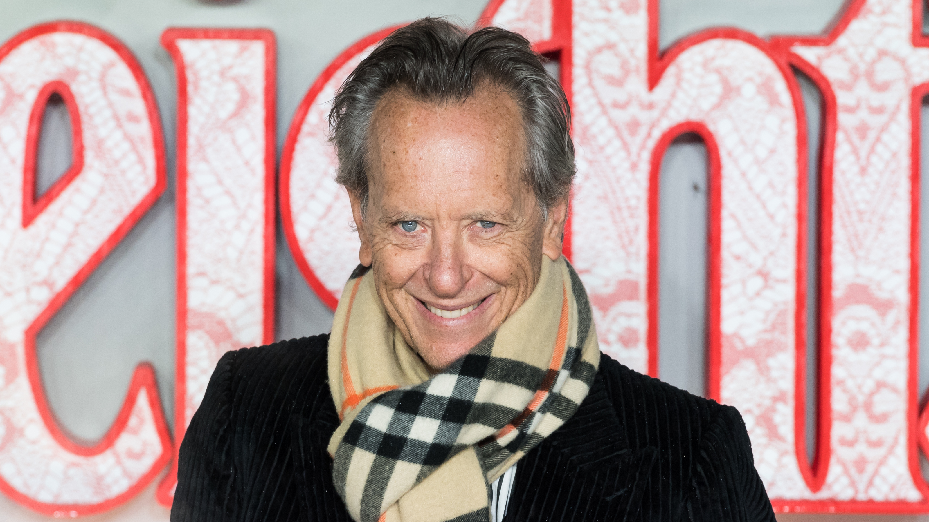 Richard E. Grant wearing trench coat and burberry scarf at Wuthering Heights premier.