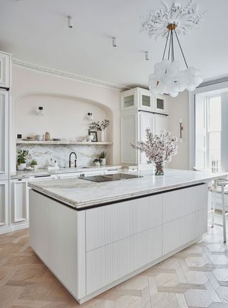 White kitchen with white walls, island and wood flooring