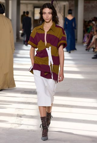 The polo shirt trend on Dries Van Noten's spring runway with a model wearing a striped rugby shirt with a white pencil skirt, printed socks, and printed pointed heels.