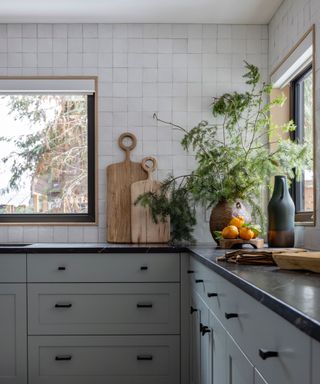 a kitchen with blue cabinets, black countertops, white square wall tiles and a white ceiling