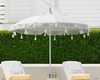 A decorative grey patio umbrella with a scalloped canopy and tassels
