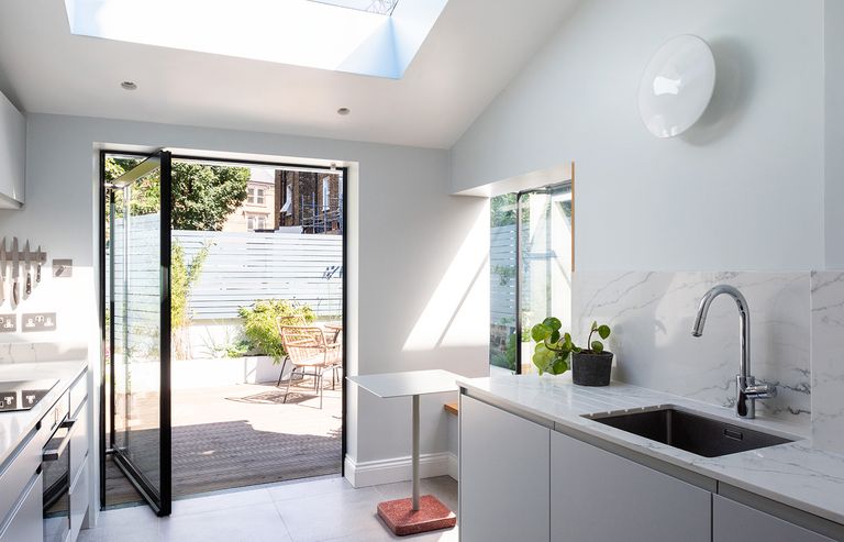 small addition ideas with a single pivot door, roof light and side box window in a white kitchen