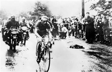 On Stage 21 of the 1958 Tour, Charly Gaul launched an audacious solo move on the Luitel, seen here at the crest of the fog-covered Col de Porte with an advantage of five and a half minutes over the chasing bunch. Riding downhill in freezing rain, the Luxembourg rider went on to win the stage in Aix-les-Bains.