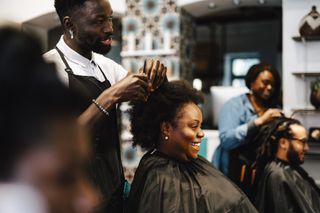 A male hairdresser is cutting a woman's hair in a salon enviroment.