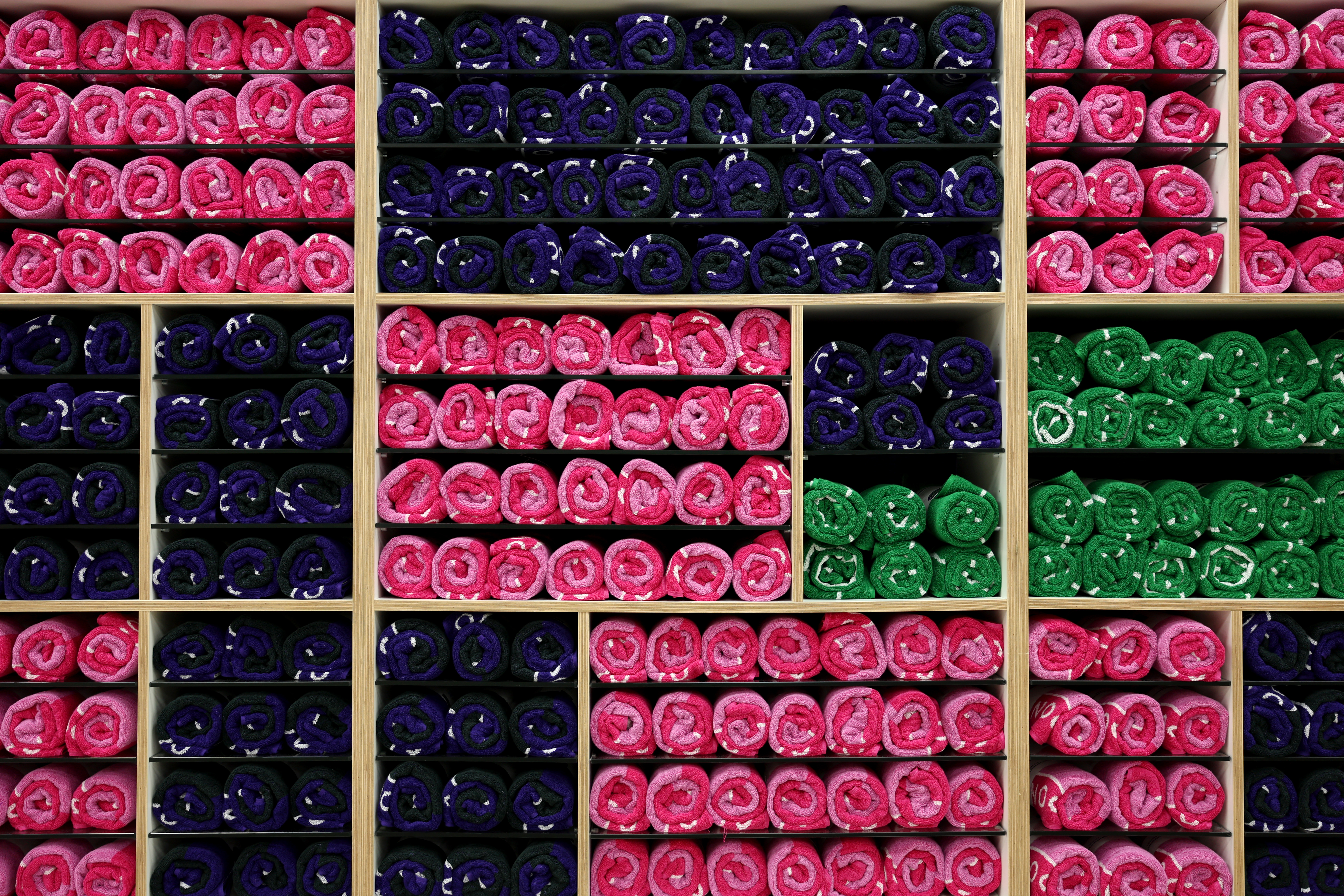 Neatly rolled up stacks of Wimbledon towels in pink, purple and green