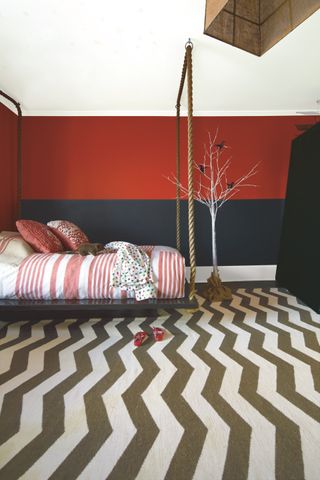 red and navy teen girl bedroom with graphic carpet, raised bed, pink stripe bedding and cushions, white tree
