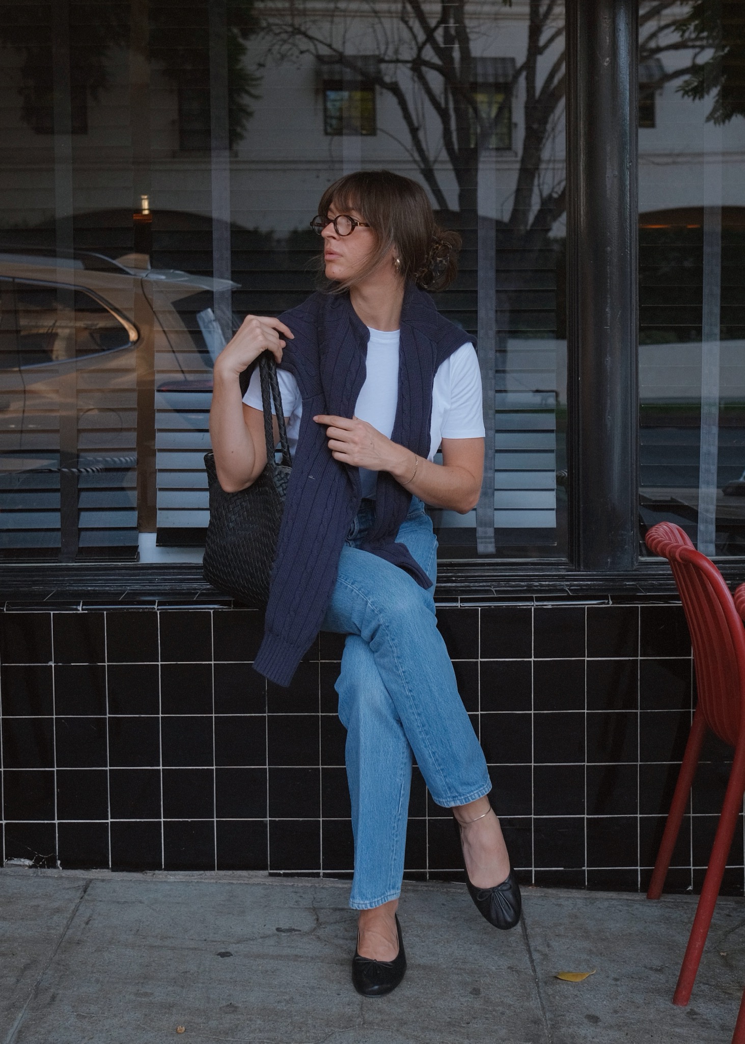 Kathryn Zahorak wearing glasses, navy sweater, white tshirt, jeans, and black ballet flats