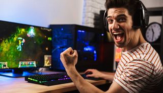 En PC-spelare sitter framför sin datorskärm och ser glad ut under en League of Legends-match.