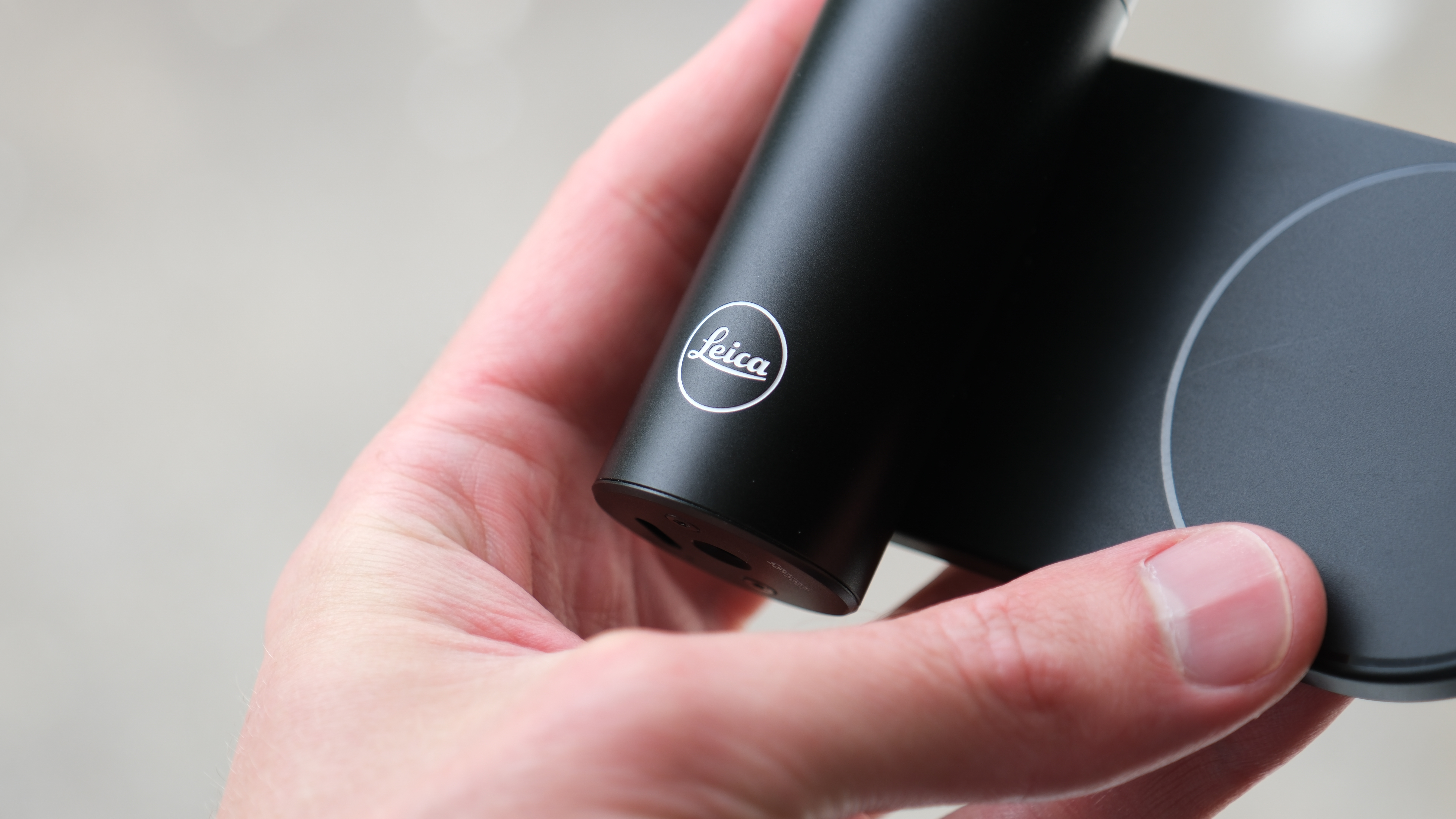 Close-up of the Leica logo on a Leica Lux Grip held in a hand