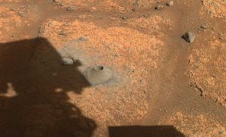 This image taken by one the hazard cameras aboard NASA’s Perseverance rover on Aug. 6, 2021, shows the hole drilled in what the rover science team calls a “paver rock” in preparation for the mission’s first attempt to collect a sample from Mars.