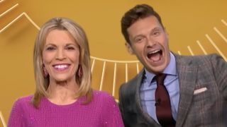 Vanna White and Ryan Seacrest standing together and smiling on Wheel of Fortune