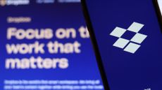 The Dropbox logo shown on a smartphone with the company's motto in the background