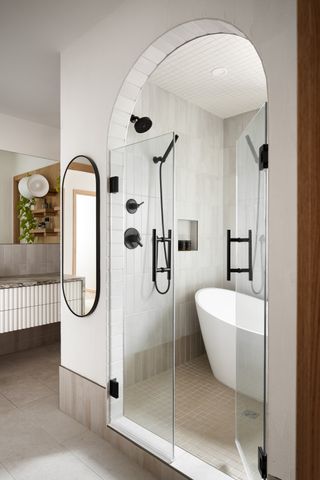 Bathroom with white tiling, separate bath and shower enclosure, black hardware and plants