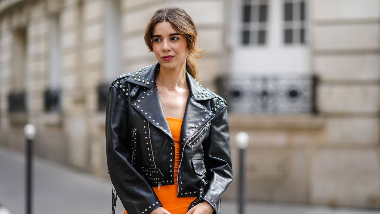 best long lasting lipstick - Ketevan Giorgadze wears a black shiny leather nailed / studded biker jacket, a gold necklace, a neon orange shoulder-off midi tube dress,