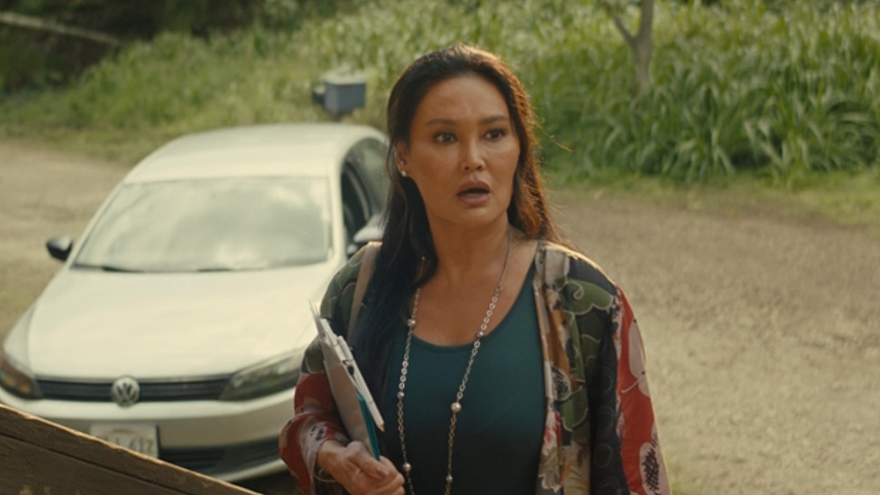 Tia Carrere in a colorful outfit looking shocked at what Lilo and Nani are up to in Lilo &amp; Stitch live action.