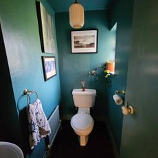 dark blue small bathroom with white toilet and gold fixtures
